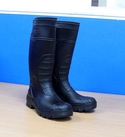 Men's black rubber boots on a blue background. High quality photoの写真素材