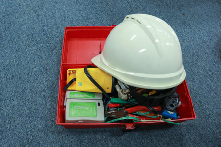 Protective helmet and electrical components in a red box on the floorの写真素材