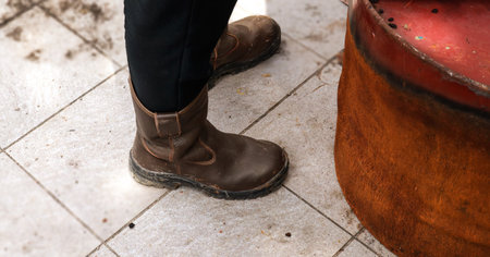 Closeup of a man's foot in a brown leather boots on the streetの写真素材