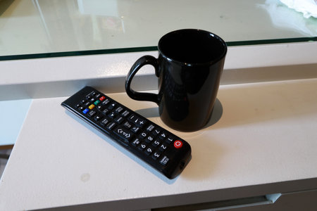 TV remote and a cup of coffee in the morning, watching tv and enjoying coffeeの写真素材