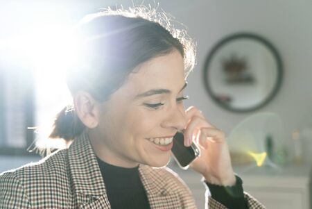 Close-up of an attractive young girl talking on the business phone while telecommuting from her home room.の写真素材