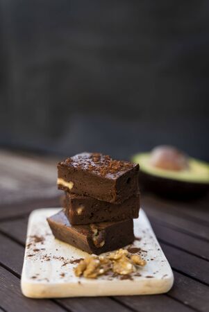 Creamy brownie with walnuts and cocoa powder. Rustic and dark background. Top view.の写真素材
