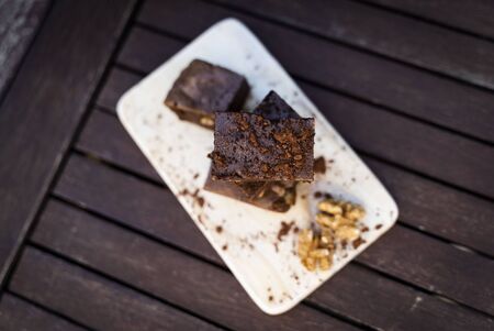 Creamy brownie with walnuts and cocoa powder. Rustic and dark background. Top view.の写真素材