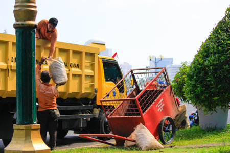 Jakarta, Indonesia - March 12 2023: Two cleaners are loading garbage into a truck in the Monas areaのeditorial素材