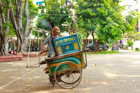 Jakarta, Indonesia - July 11 2023: An old man selling Rangi cakesのeditorial素材