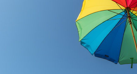 Close up of colorful beach umbrella under blue skyの素材