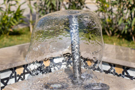 Little fountain. Transparent falling water vertical flows, close upの写真素材
