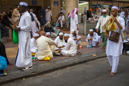 Mecca - Saudi Arabia: 24 August 2018. Muslim pilgrims in streets of Mecca city. People eating street food on the pavementのeditorial素材