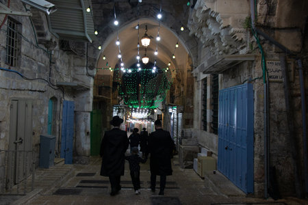 Night view of ancient street in the old city of Jerusalem - Israel: 21 April 2022. Jewish families walking on the street of old cityのeditorial素材
