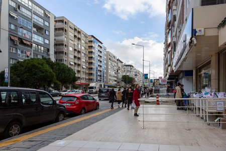 Izmir, Turkey-January 13, 2021: central street of Guzelyali District of Konak district of Izmir, with residential buildings. The Gulf of Izmir on the Aegean Sea. People walking around outside.のeditorial素材