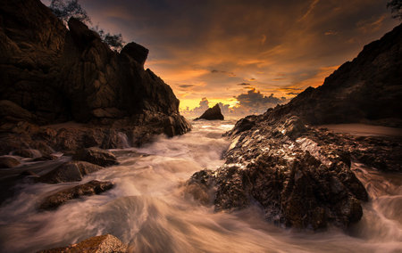 Long exposure of beautiful sunset over the sea with rocks and waves.