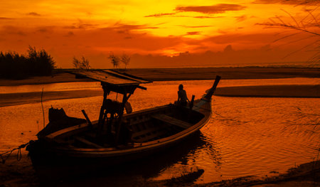 Silhouette of fisherman boat on the river at sunset, Thailand.の写真素材