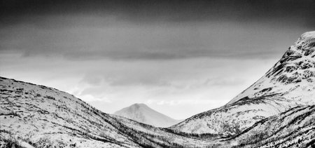 Black and white panoramic view of snow covered mountains in Scotland.
