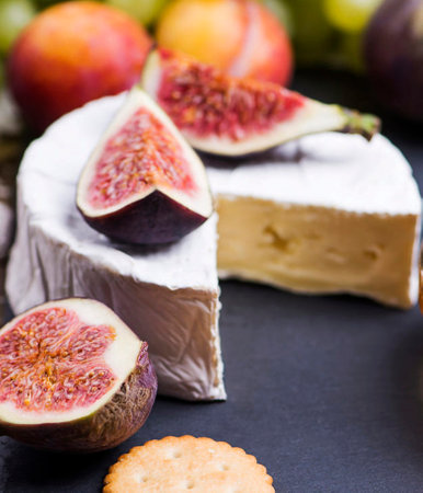 Camembert cheese with figs and grapes on a black backgroundの写真素材