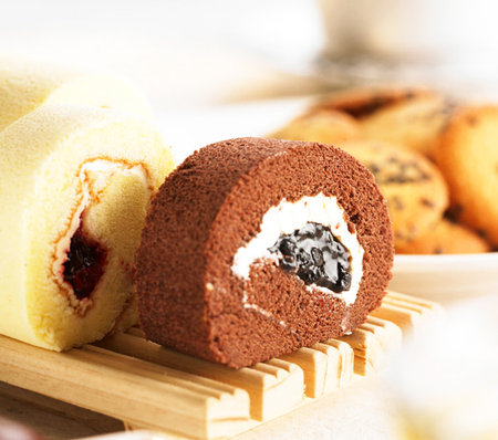 Chocolate roll cake with jam on a wooden board. Shallow dof.の写真素材