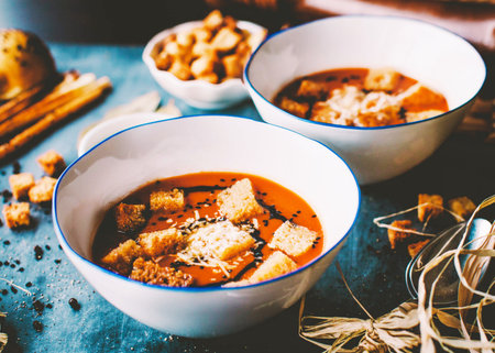 Tomato soup with croutons and spices in white bowls.の写真素材