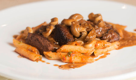 pasta with mushrooms and sauce on a white plate in a restaurantの写真素材