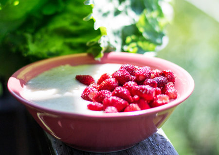 Creamy yogurt with strawberries in a bowl on a wooden tableの写真素材