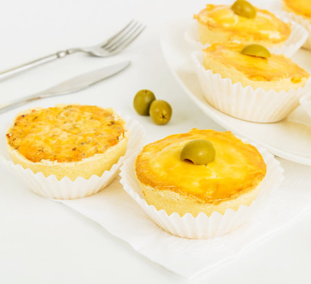 tartlets with cheese and green olives on a white background