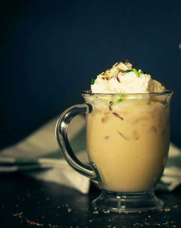Iced coffee with whipped cream and green onions on a dark background