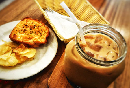 Coffee in a glass jar with crackers on a wooden tableの写真素材