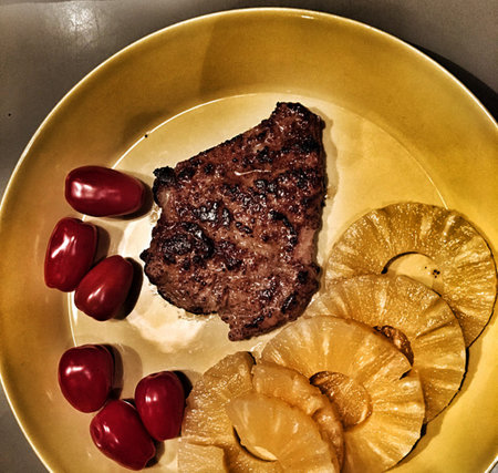 grilled beef steak with pineapple and red pepper on a yellow plateの写真素材