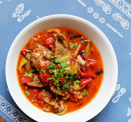 pork stew with vegetables in white bowl on blue tablecloth backgroundの写真素材