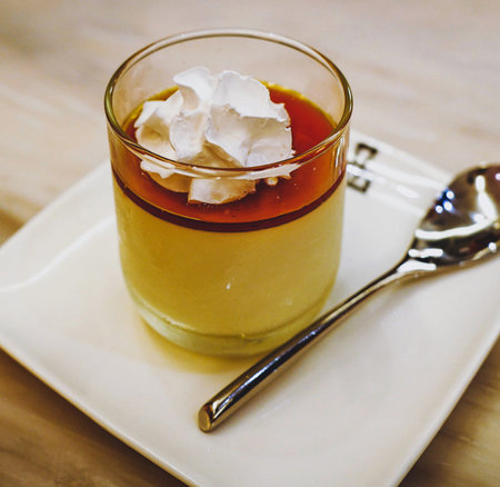 Panna cotta with whipped cream in a glass on wooden tableの写真素材