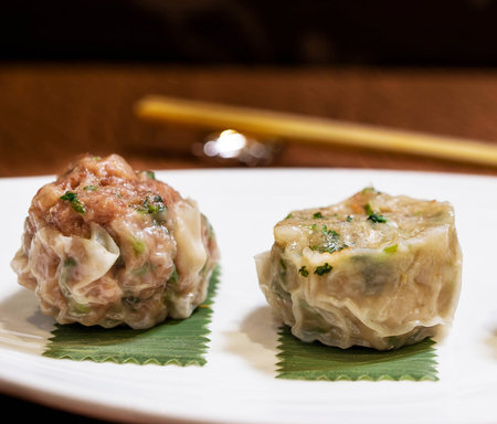 Chinese steamed dumplings on a white plate with chopsticksの写真素材