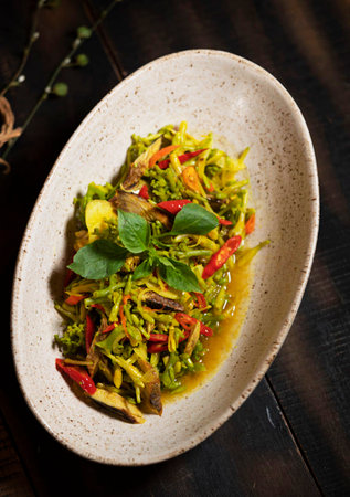 Thai spicy green curry with chicken and vegetables on rustic background