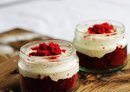 Red velvet trifle in a glass jar on a wooden table.の写真素材