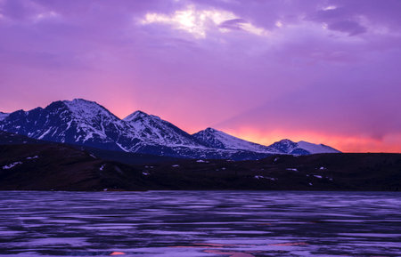Beautiful sunset over a frozen lake with snowy mountains in the background