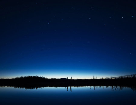 Night sky with stars and silhouette of a man on the lake.の写真素材
