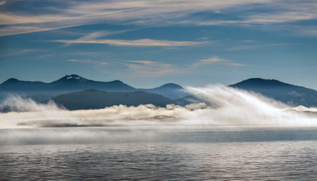 Foggy morning on the lake. Mountain range in the background.の写真素材