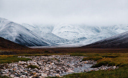 Icelandic landscape with river and snow covered mountains in the backgroundの写真素材