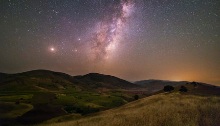 Milky way and stars over the hills in the countryside. Long exposure photograph.