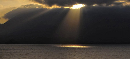 Sunset over the sea with sun rays in the clouds, natural background
