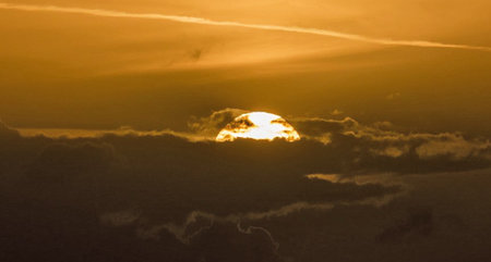 Sunset in the sky with clouds. The sun sets behind the clouds.の写真素材