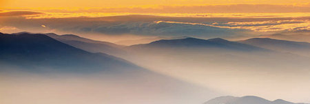 Panoramic view of the mountains in the fog at sunset.の写真素材