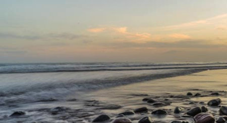 Sunset on the beach with pebbles and sea waves.の写真素材
