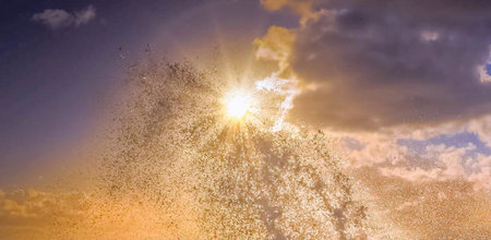 Falling snowflakes against blue sky with sun in the background