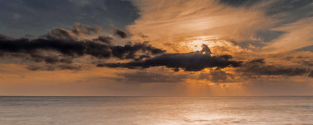 Panoramic view of a sunset over the sea with dramatic clouds