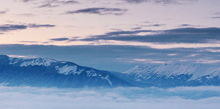 Mountains in the clouds at sunset. Panoramic view.