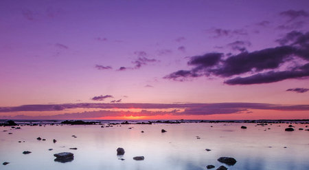 Sunset over the sea with rocks and reflection in the water.の写真素材