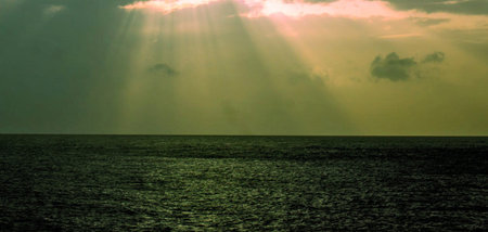 Sunset over the sea with rays of light passing through the clouds