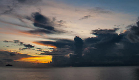 Sunset over the sea in the tropics. The sun sets behind the clouds.の写真素材