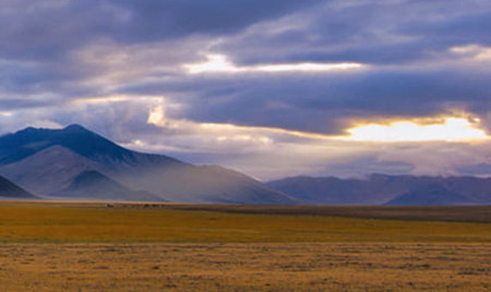 Mongolian landscape with grassland and mountains under cloudy skyの写真素材