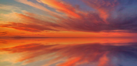 Beautiful sunset over the sea with clouds reflected in the water.