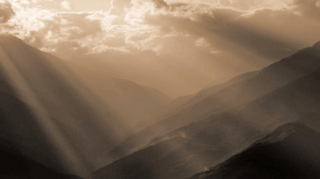 Sun rays through the clouds over the mountain peaks. Toned.の写真素材