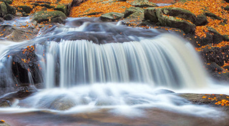 Beautiful waterfall in autumn forest with colorful leaves, long exposure.の写真素材